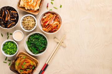 Assorted korean food and chopsticks on wooden background