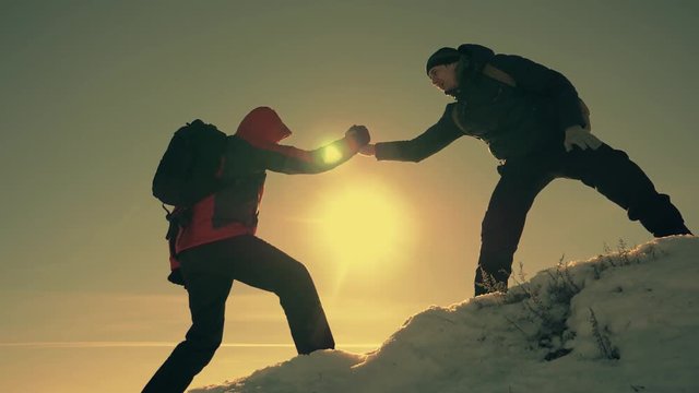 Tourist helping teammate climb, the man with the backpack reached out a helping hand to his friend. Teamwork concept. Teamwork, help in difficult situations