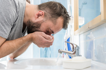 Man washing his face in bathroom