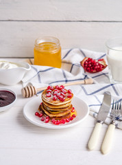 Pancakes with pomegranate seeds, honey and powdered sugar