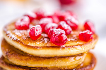 Pancakes with pomegranate seeds, honey and powdered sugar