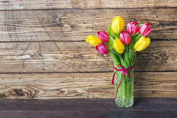 Bouquet of yellow and pink tulips on a wooden background.