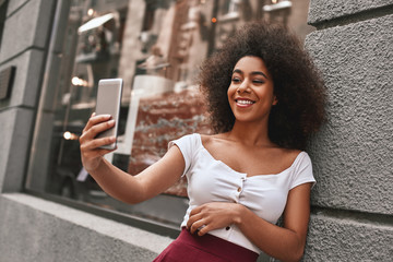 Creating happy memories. Attractive and young Afro American woman taking selfie while spending time...