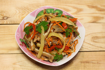 Salad of carrots and pork ears in a plate on a wooden table