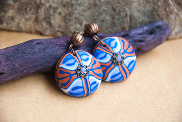 Fototapeta na wymiar Handmade jewelry from polymer clay. Floral Ethnic earrings with unique pattern. Fashion jewelry.Still life in boho style. Trendy accessory.