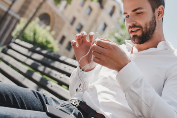 Sometimes the most productive thing you can do is relax. Handsome man holds his earphones while...