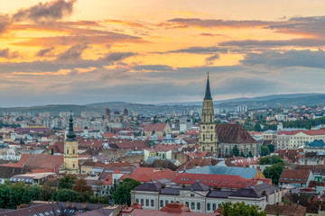 Fototapeta na wymiar The old city of Cluj-Napoca with the Franciscan Church and St. Michael's Church viewed from Cetatuia Park at sunrise in Cluj-Napoca, Romania