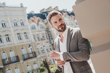 Wake up with determination. Go to bed with satisfaction. Smiling brown-haired man standing outdoors and looking away