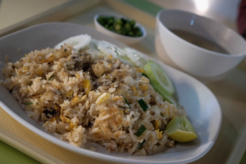 Fried rice with chicken. Prepared and served in a wok. Natural wood in the background. Top view.