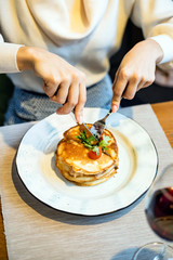 Young woman having breakfast and cut pancakes