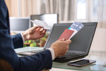 Man holding airline ticket and passport buying on the Internet using a laptop. Purchasing and booking tickets online
