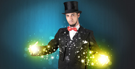 Handsome illusionist holding his superpower on his hands with gold wallpaper