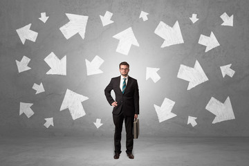 Handsome businessman standing in front of a wall with chalk drawn arrows