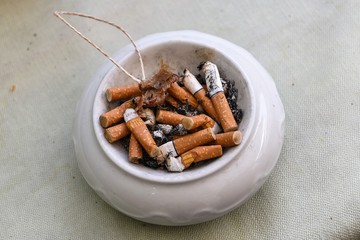 Abstoßend, Häßlich, Ungesund- Aschenbecher mit Zigarettenkippen als Symbol für die abnehmende Attraktivität des Rauchens