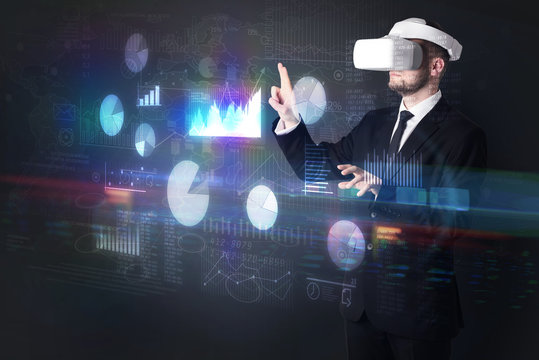 Elegant businessman in DJI goggles handling 3D reports and charts around him

