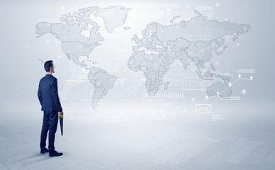 Fototapeta premium Businessman standing with his back and looking at a worldwide map with objects in his hand 