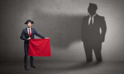Businessman standing with red cloth on his hand and his shadow on the background
