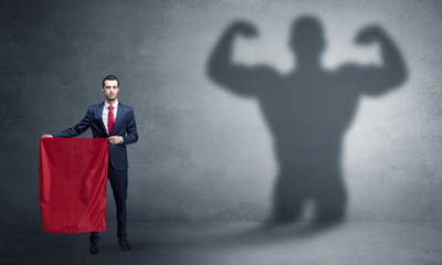 Businessman standing with red cloth on his hand and strong hero shadow on the background
