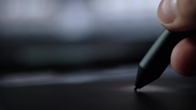 Close-up of hand drawing on a digital tablet with pencil.