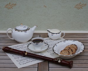 English teacup with saucer, teapot, cream jug and a cake bowl, fine bone china porcelain, and a block flute on a sheet of music