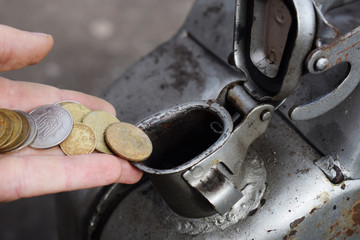 Payment for the gas, fuel, gasoline, diesel concept. Hand dropping money, coin in the can of fuel