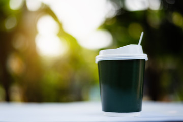 A paper cup of hot coffee with smoke at sunrise