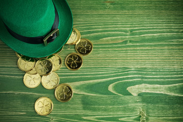 Happy St Patricks Day leprechaun hat with gold coins on vintage green wood background