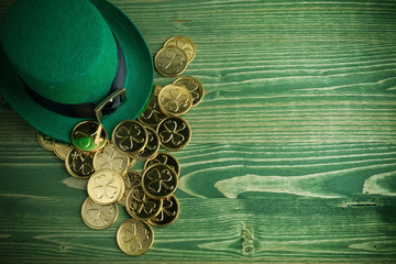 Happy St Patricks Day leprechaun hat with gold coins on vintage green wood background