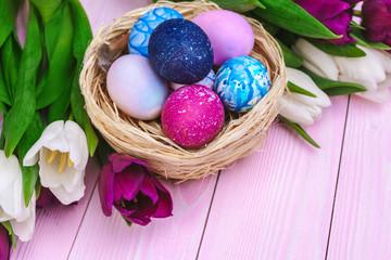 Easter eggs in a nest and tulips on wooden planks