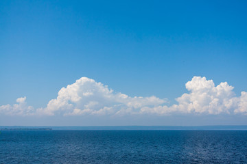 Blue sky with clouds above the water surface.