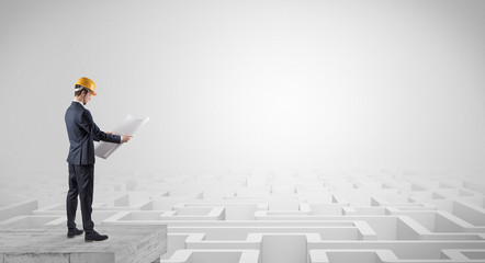Architect standing on maze and looking at a future plan
