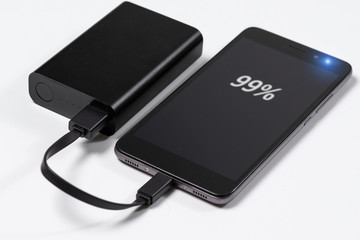 smartphone is charging from the black battery power bank
