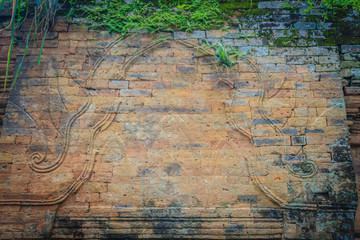 Old ruin brick wall covered with green moss and small grass. Old khmer sanctuary brick wall overgrown with green moss.