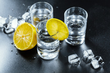 Cold vodka in shot glasses on a black background.