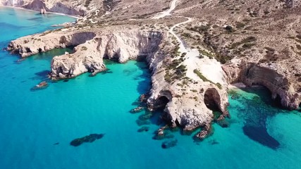 Aerial drone bird's eye view video of iconic volcanic white chalk beach and caves of Tsigrado with turquoise and sapphire clear waters, Milos island, Cyclades, Greece - Powered by Adobe