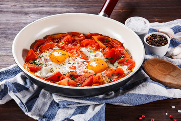 Shakshuka - fried eggs with vegetables in frying pan