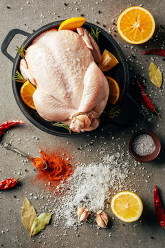 top view of raw chicken with oranges and spices in griddle pan