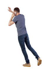 back view of walking man . guy going, pointing and talking on smartphone.