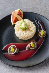 rice, broccoli, fig and fried meat with sauce on black plate and stone surface