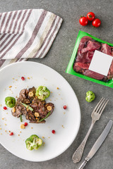 top view of broccoli and fried meat on white plate and raw meat on table