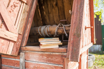 A stack of vintage books lie on a wooden old well