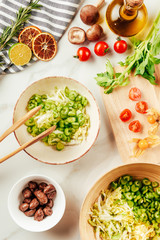 cherry tomatoes on cutting board with cabbage and celery in plates with oil, lime and greenery