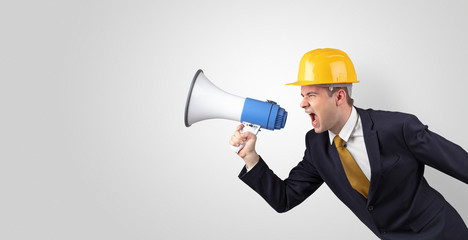 Young architect constructor yelling with megaphone and copyspace