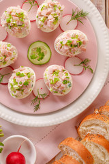 Deviled eggs, stuffed eggs filled with a paste made from smoked ham, mayonnaise, egg yolks and fresh chive on a plate, top view. Tasty breakfast, appetizer for party or holiday meals