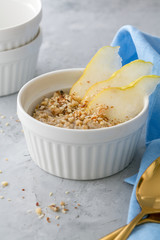 Healthy breakfast: oatmeal porridge in  bowl with sliced pear. Selective focus