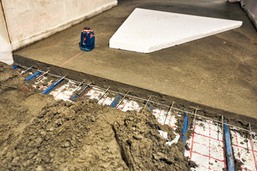 Laying blue pipes for floor heating at the construction site.