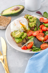 Healthy Breakfast with avocado toasts, poached egg and salad. Selective focus