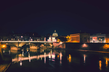 Night view of the Rome.In foreground the Tiber river and its amazing bridges and in background the dome of St Peter's basilica.