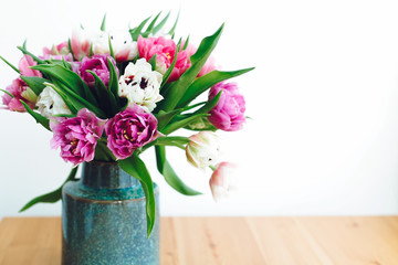 Beautiful double peony tulips in light. Colorful pink and purple tulips bouquet in vase on table with copy space. Happy mothers day. International women's day. Hello Spring. Greeting card