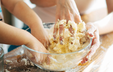 Hands of mother and child making dough